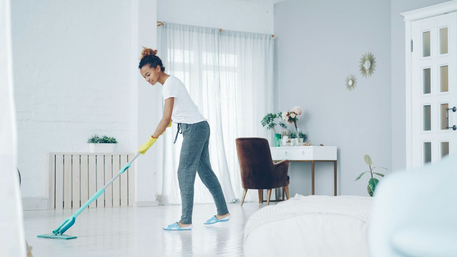 A cleaner mopping the floor of a bright living room